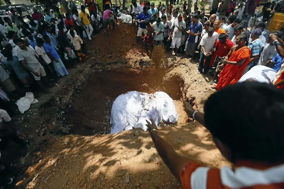 Local villagers prepare to bury the body of elephant Hemantha during a religious ceremony at a Buddhist temple