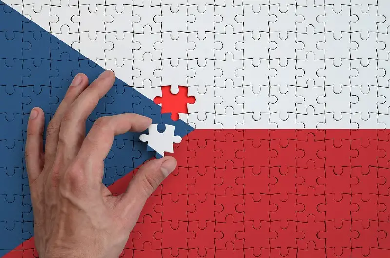Czech flag is depicted on a puzzle, which the man's hand completes to fold