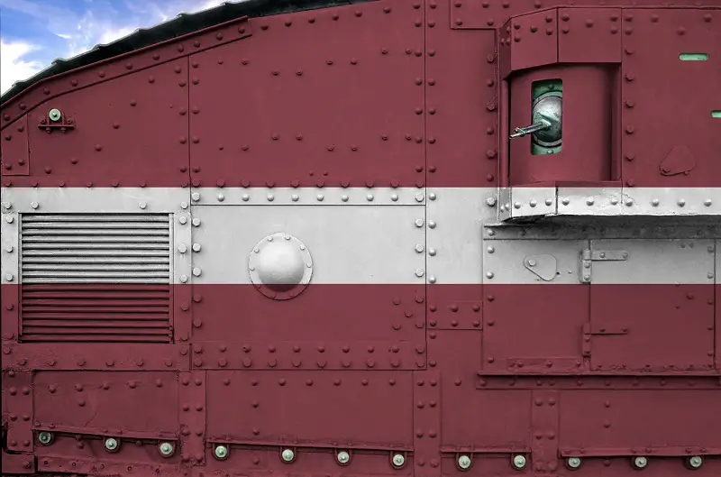 Latvia flag depicted on side part of military armored tank closeup. Army forces conceptual background