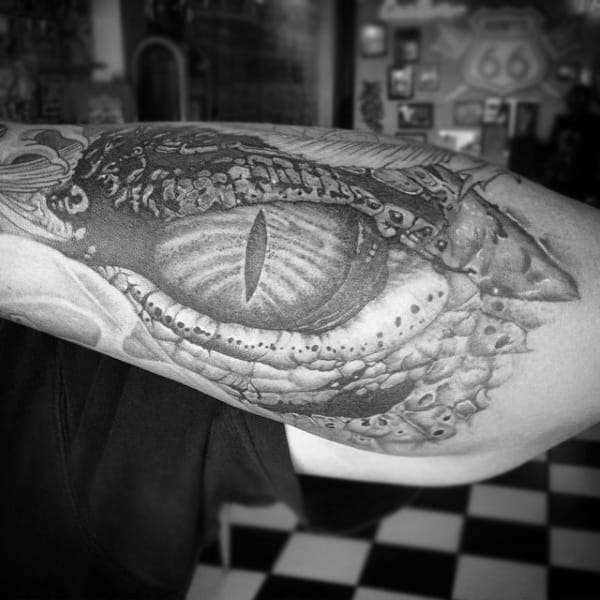 shaded-black-detailed-godzilla-eye-tattoo-on-guys-forearm