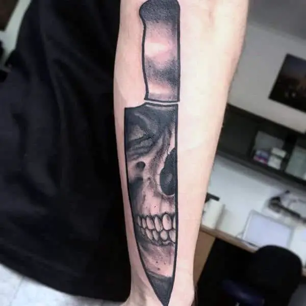 man-with-skull-chef-knife-tattoo-on-outer-forearm