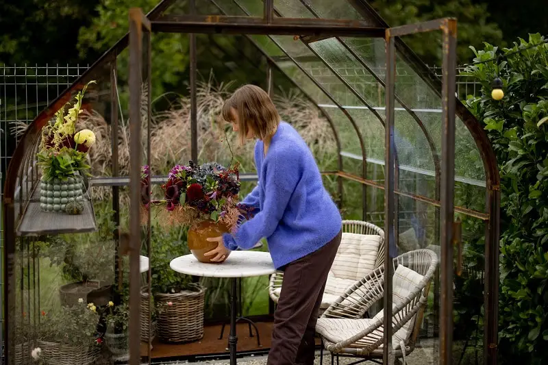 Woman florist makes a beautiful bouquet in glasshouse at back yard