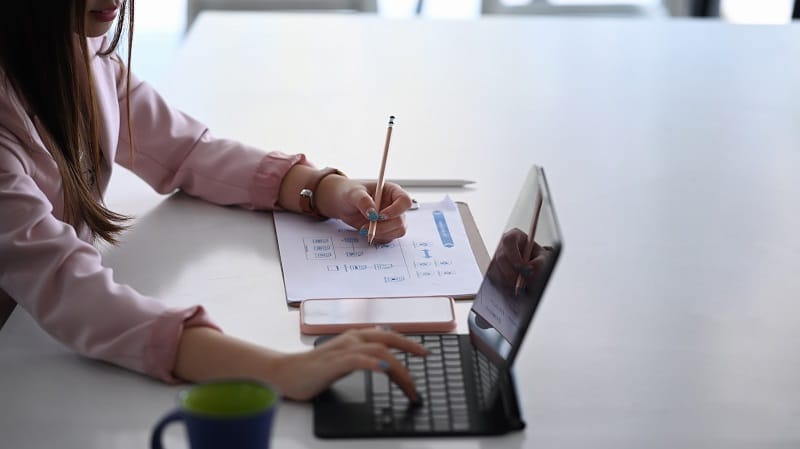 Close up view of businesswoman writing on paperwork and searchin