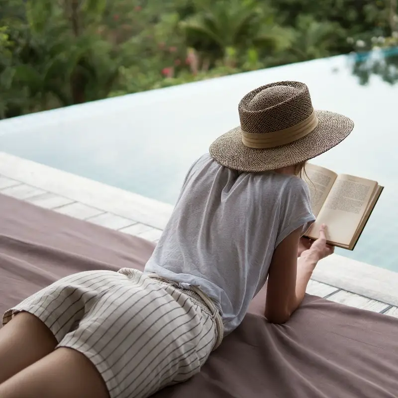 Young girl reads a book near the pool
