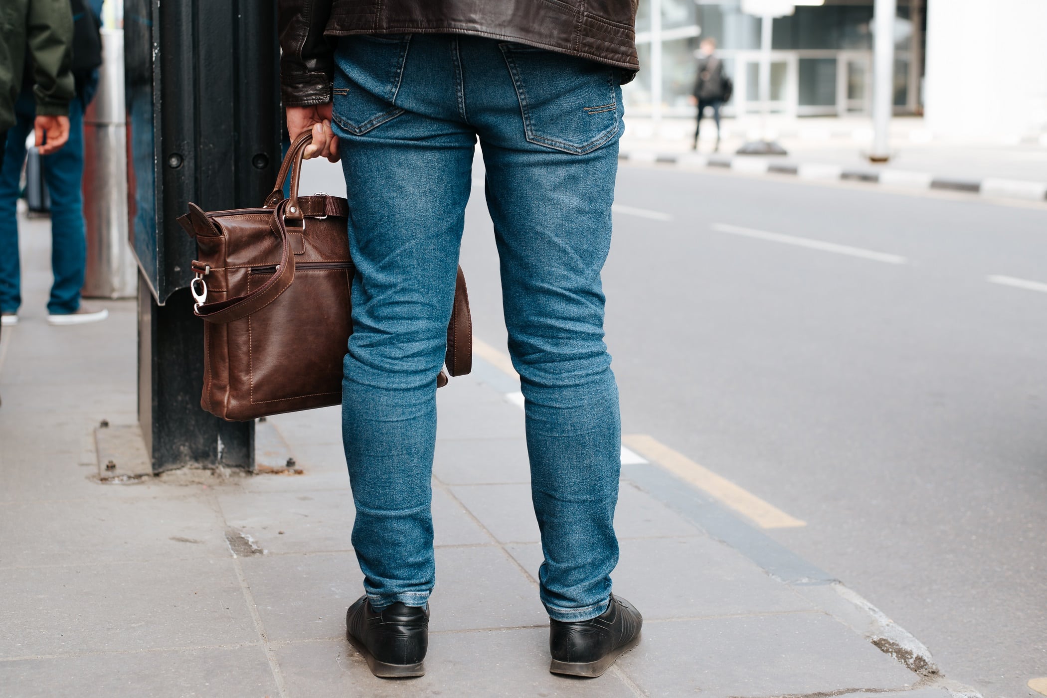 Business casual man standing on the sidewalk waiting. Close-up, rear view, selective focus